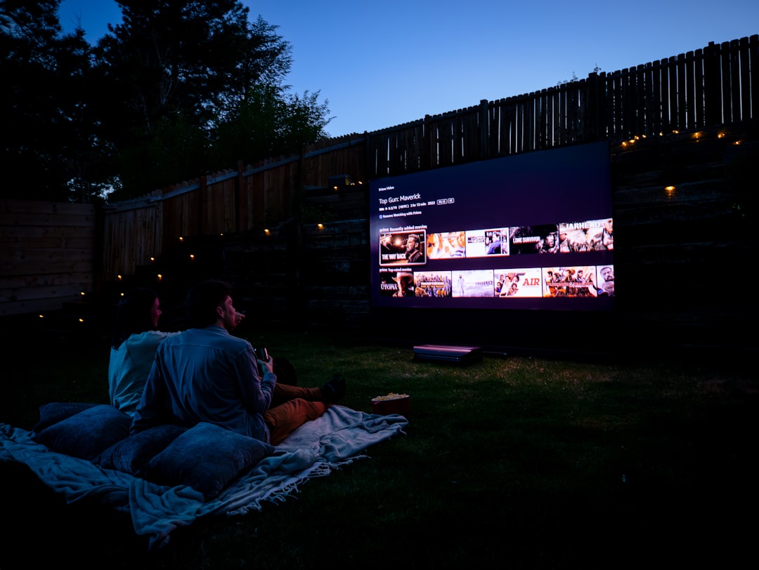 Two people sitting on a blanket, immersed in a movie experience enhanced by AWOL Vision 4K UST projector.
