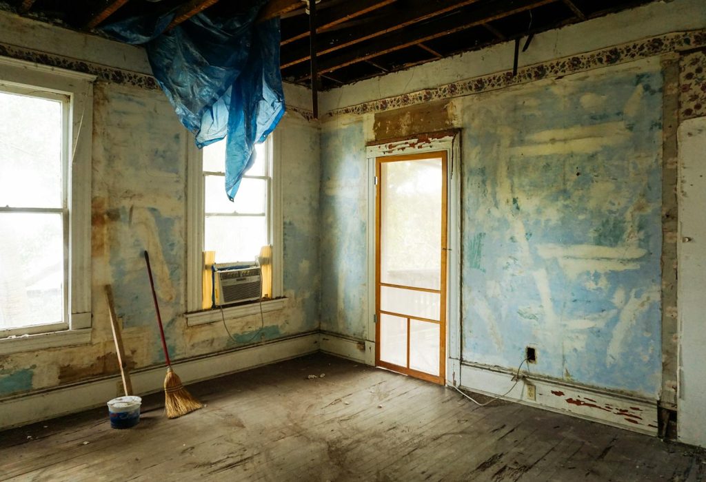 Photo by Monica Silvestre An empty room in an abandoned house with peeling walls and construction tools.