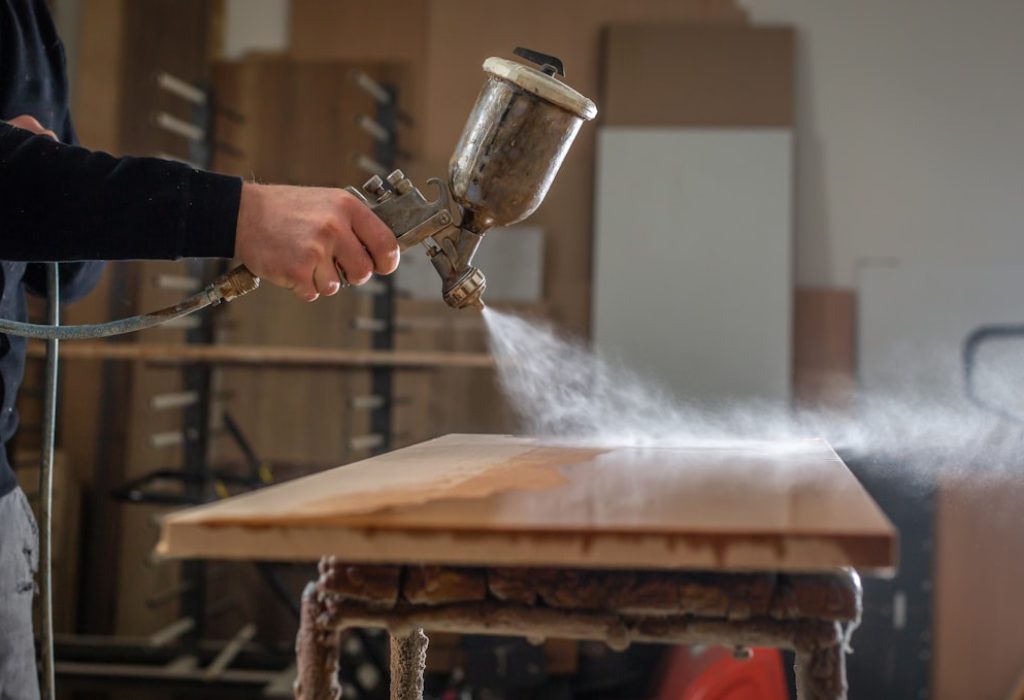 Staining wood with white spray gun, application of flame retardant ensuring fire protection, airless spraying device, industrial concept
